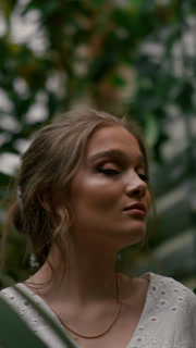 Attractive young woman standing in a lush green botanical garden