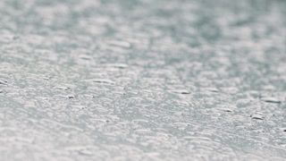 Raindrops on a window create a blurred and textured surface on a rainy day