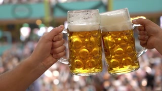Two glasses of beer are being cheered in a crowd
