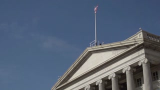 Exterior view of a government building with flag against a blue sky