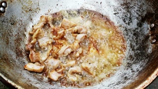 Chicken pieces frying in hot oil inside a wok on a stove for a tasty meal prep