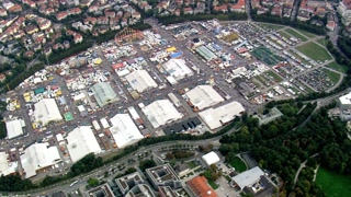 Aerial view of a large outdoor event with tents in a city surrounded by trees