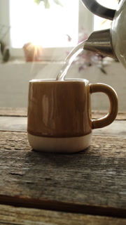 Vertical video. Tea time. Pouring boiling water from kettle into tea cup