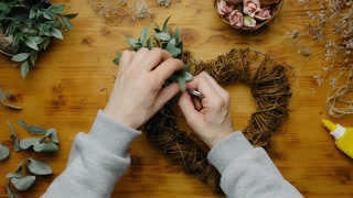 Female hands making flower arrangement. Heart shaped Spring floral wreath. DIY home decor crafts.