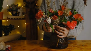 Woman creates Valentine's bouquet with red flowers.