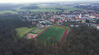 Aerial view of stadium in small town, Players play football on soccer field