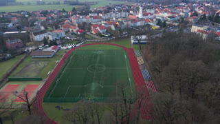Aerial view of stadium in small town, Players play football on soccer field