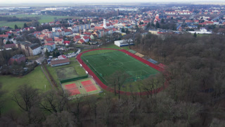 Aerial view of stadium in small town, Players play football on soccer field