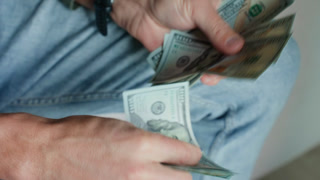 Man counting stack of one hundred dollar bills