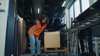 Woman, a logistics and warehouse worker suffering from back pain after manual handling, lifting, and carrying heavy cardboard box.