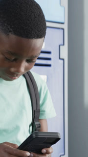 Vertical video: Starting student scrolling device by school lockers in mint shirt and backpack