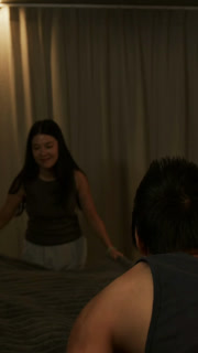 Vertical video: Picking duvet, woman in tank top and light pants smoothing it across bed making bed
