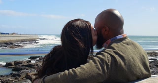 Couple kissing on bench near railing on a sunny day 4k