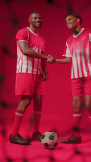 Two African American men red kits after shot slapping hands, posing back-to-back with ball for ad