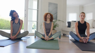Vertical video: Cue starting, trio are sitting on mats at home mirroring neck rolls easing tension