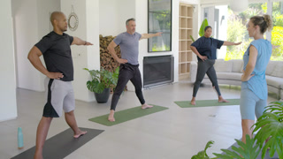 Instructor cueing wide stance and side bend, participants mirroring on yoga mats for mobility