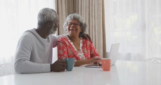 A senior African american couple spending time together working on a laptop in social distancing