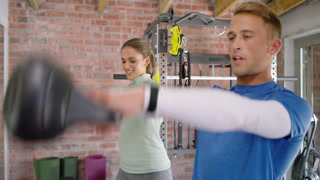 Diverse workout partners performing kettlebell swings starting from hip hinge for power in home gym