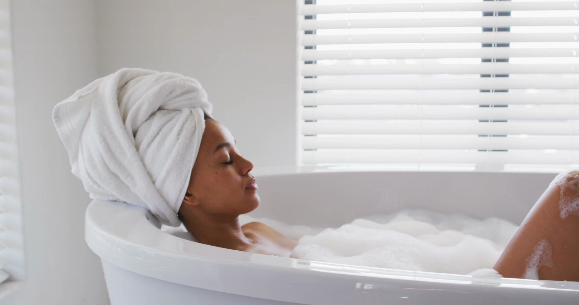 African american woman relaxing in the bath tub in the bathroom at home