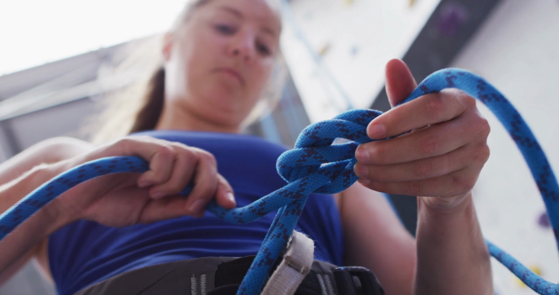 Low angle view of caucasian woman knotting rope in a harness belt at