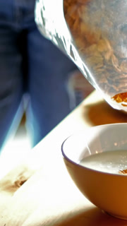Couple pouring cornflakes in bowl in kitchen