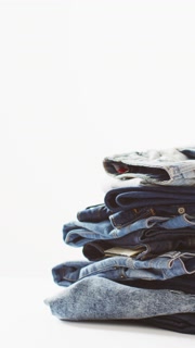 Vertical video of folded jeans with different shades on white background with copy space