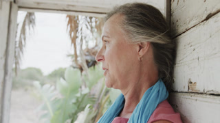 Portrait of happy senior caucasian woman relaxing on porch of wooden beach house, in slow motion