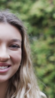 Vertical video of portrait of happy woman smiling in garden, slow motion, copy space