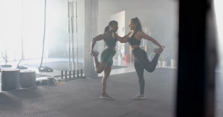 Stretching together, two women in gym wearing sportswear preparing for workout