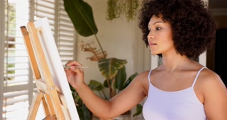 Painting on canvas, woman creating artwork in home studio with plants