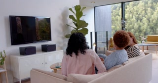 Watching television, diverse female friends sitting on couch and enjoying time together, copy space