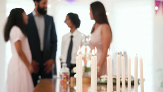 diverse family celebrating traditional ceremony, embracing with lighting candles on table at home
