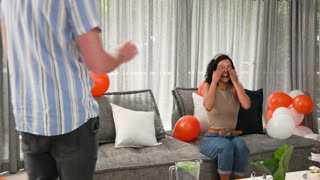Happy diverse couple blowing candle on cupcake and celebrating at a birthday party in living room