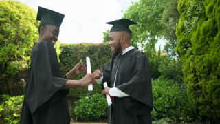 African American couple in graduation gowns celebrating success in garden