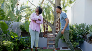 African American man proposing to woman in garden, both looking joyful and excited