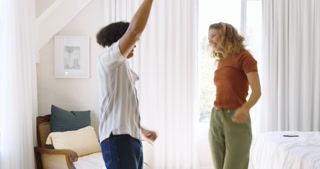 Dancing joyfully at home, diverse couple sharing lively moment together