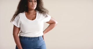Camera zooming out showing African American woman modeling jeans and ribbed T-shirt in studio