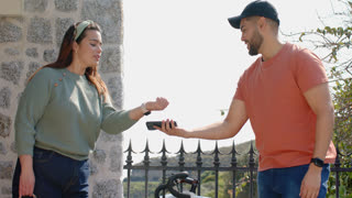 Friends paying by aligning smartphone near smartwatch outside fence by bicycle then waving farewell