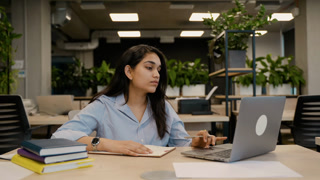 Young Indian woman studying remotely in a modern office coworking space