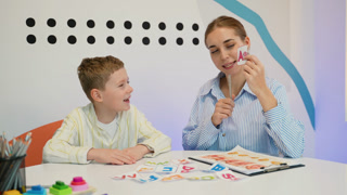 Speech therapist working with young boy pronouncing sounds