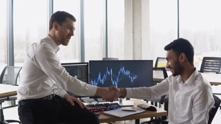 Two multiracial investors brokers indexes online cryptocurrency stock. Diverse managers traders discussing financial growth market at desk