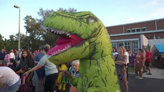 Orlando, Florida, USA - 10. 30. 2024: Two smiling inflatable characters sit on a big orange pumpkin at a school parking-lot Halloween event