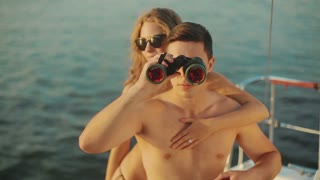 Bride and groom on their honeymoon. Guy watching through binoculars from the boat. Pirates of the sea. Honeymoon on the yacht. A date on a yacht.