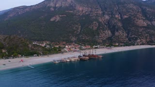 Aerial panoramic view from drone of coastal town and mountains. Yachts and boats parked on the beach of resort town.
