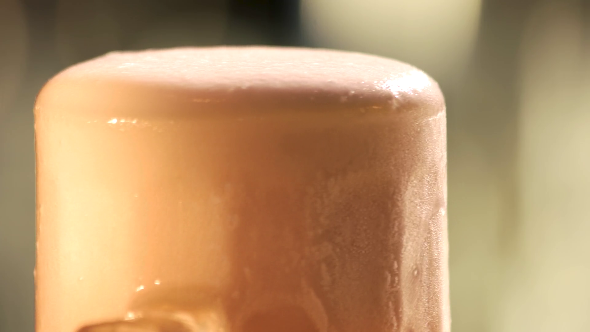 Beer foam motion. Slowly dripping beer foam out of glass, close up