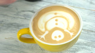 Hand of barista, latte art. Snowman picture on coffee foam.