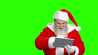 Kind santa is telling a poem to someone. Santa is using a tablet. Green hromakey behind the santa.
