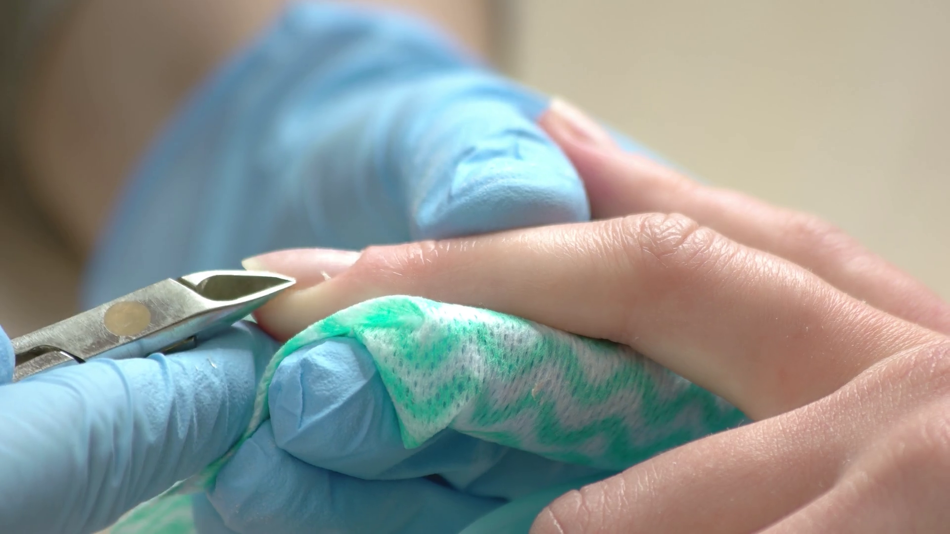 Manicurist cutting cuticle close up. Nail beautician in blue gloves