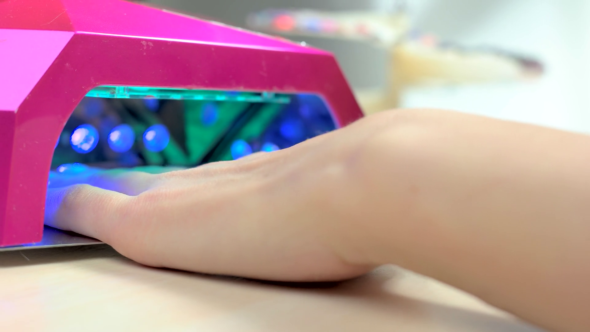 Woman drying nails in special machine. Client in manicure salon dryes