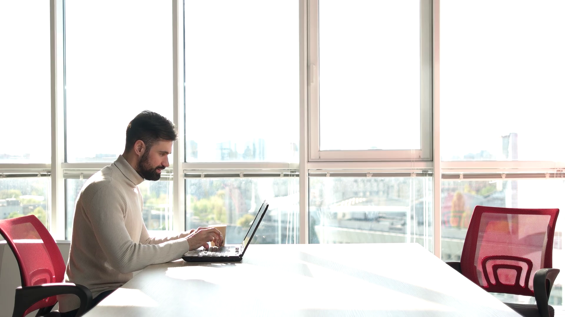 Young bearded man working as freelancer on laptop. Man working on